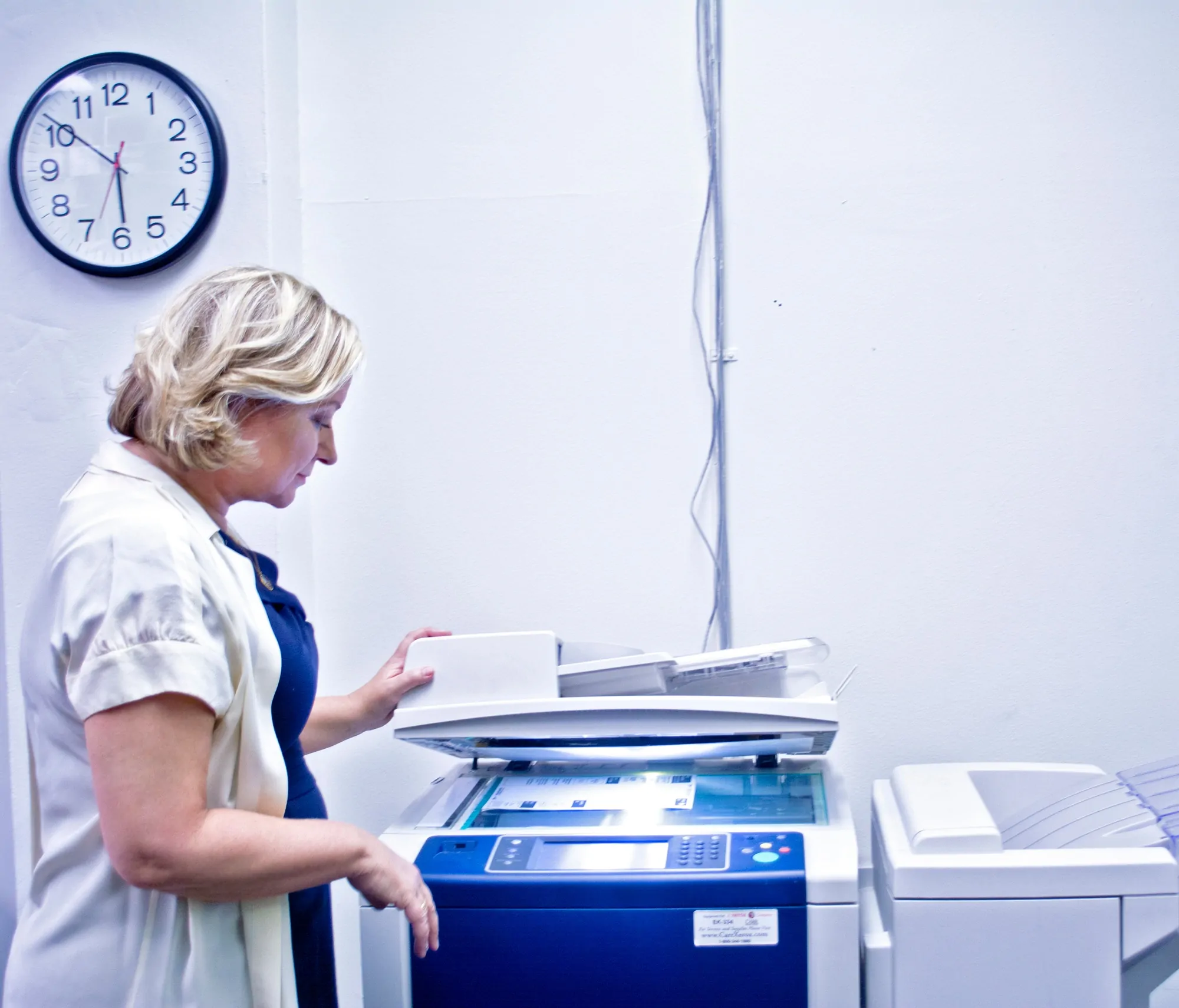 A woman operating a photocopy machine in an office setting.